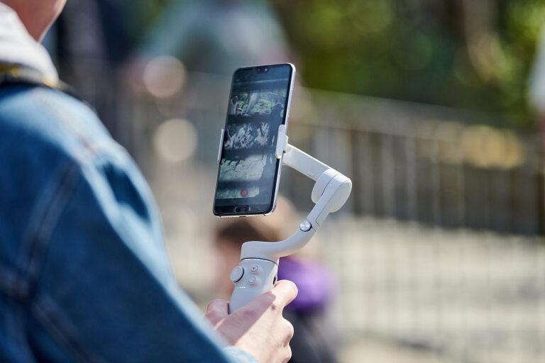 Dettaglio di una persona regge uno stabilizzatore per telefono mentre filma un video all'aperto