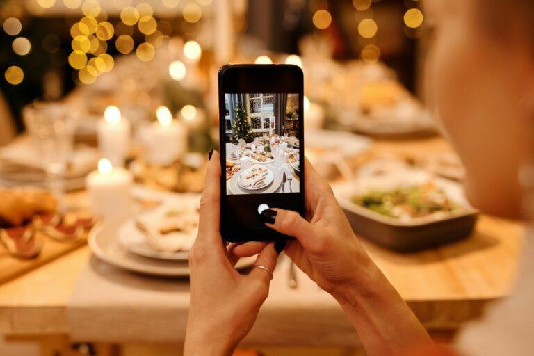 donna fa una foto con il cellulare alla tavola imbandita per Natale